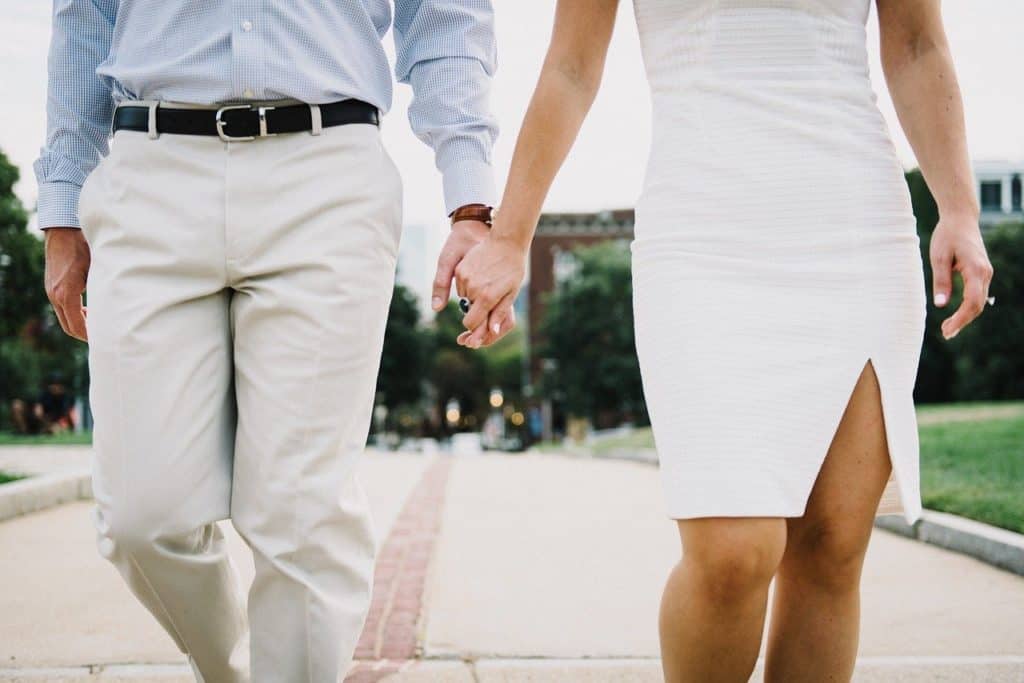 An adult couple holding hands, and dressed nicely
