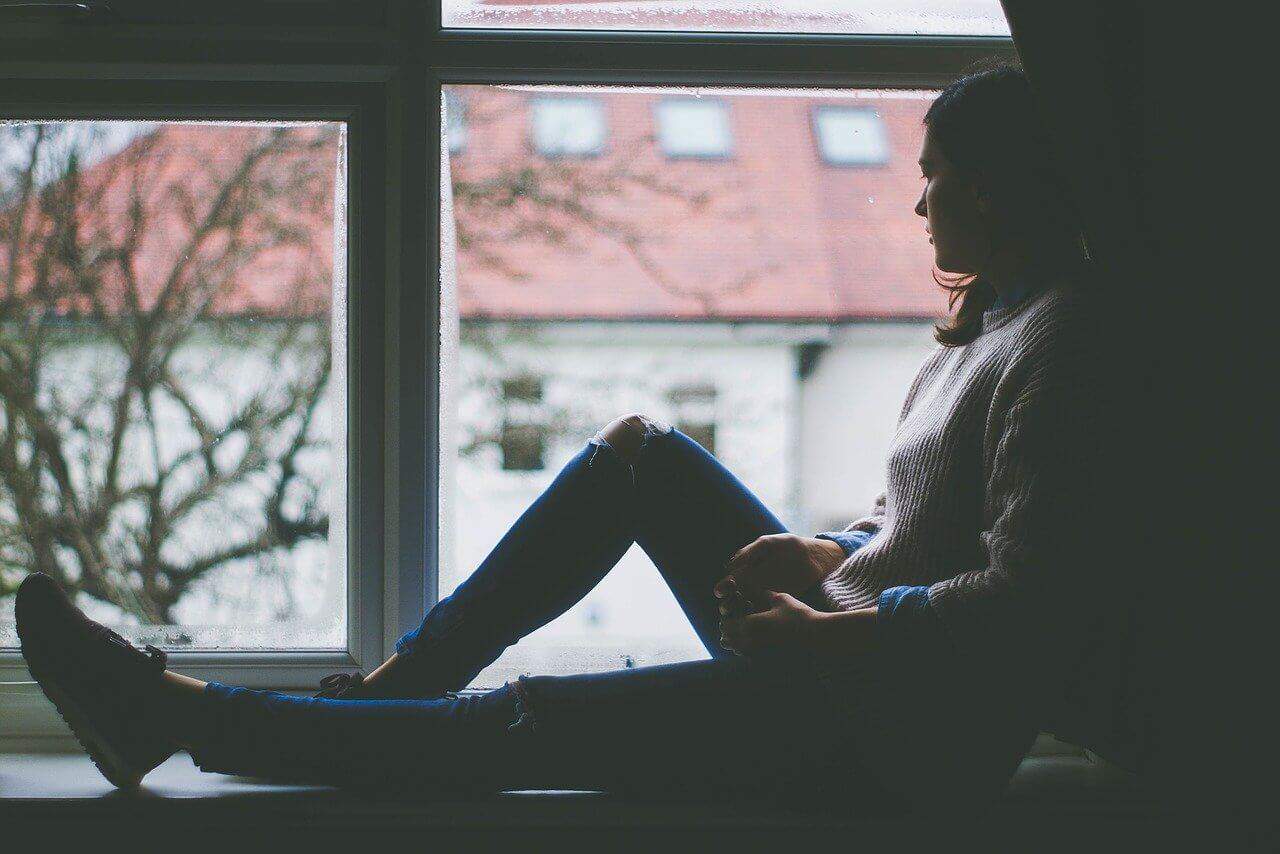 Woman sitting by window looking sad because she failed IMAT exam