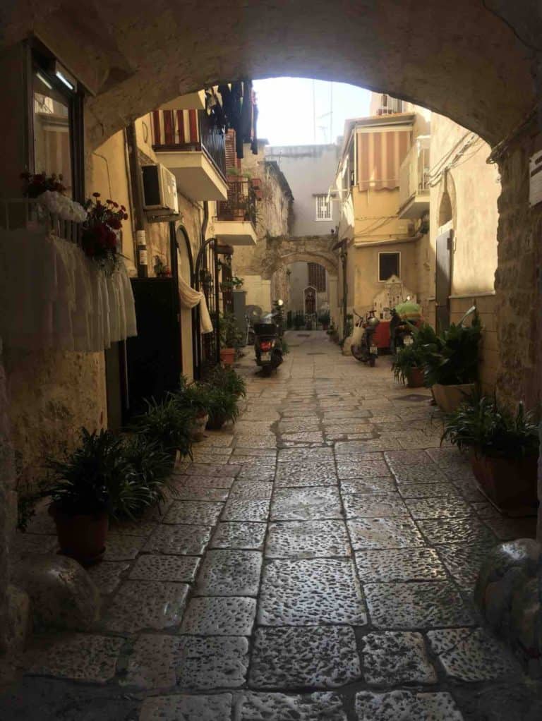 a picture of a quiet street and overhanging arch in Bari city located next to bari medicine and surgery in english programme