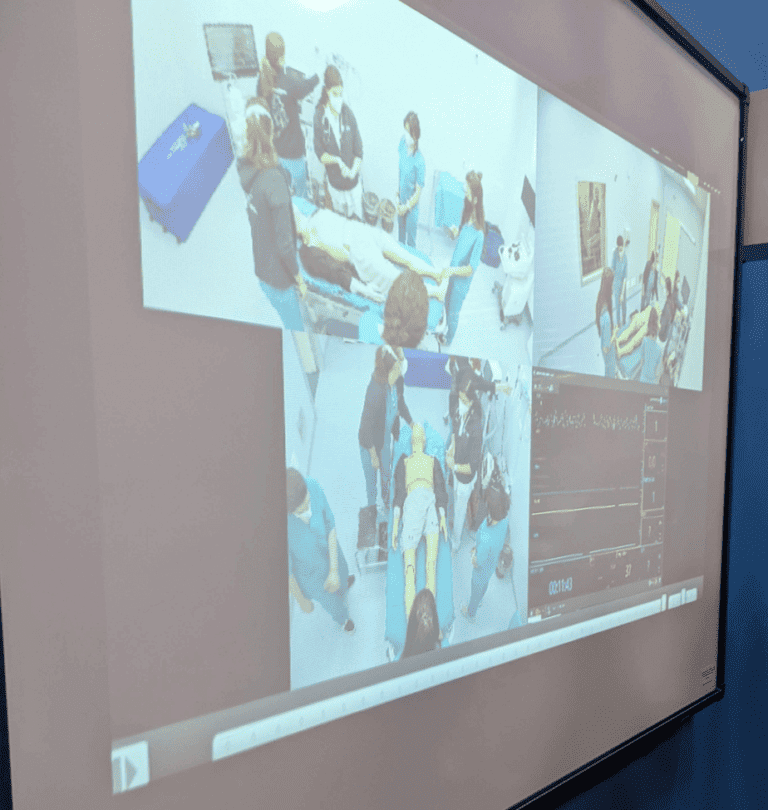 A projector screen showing three different angles of a medical simulation ran in la sapienzas new medical skill centre